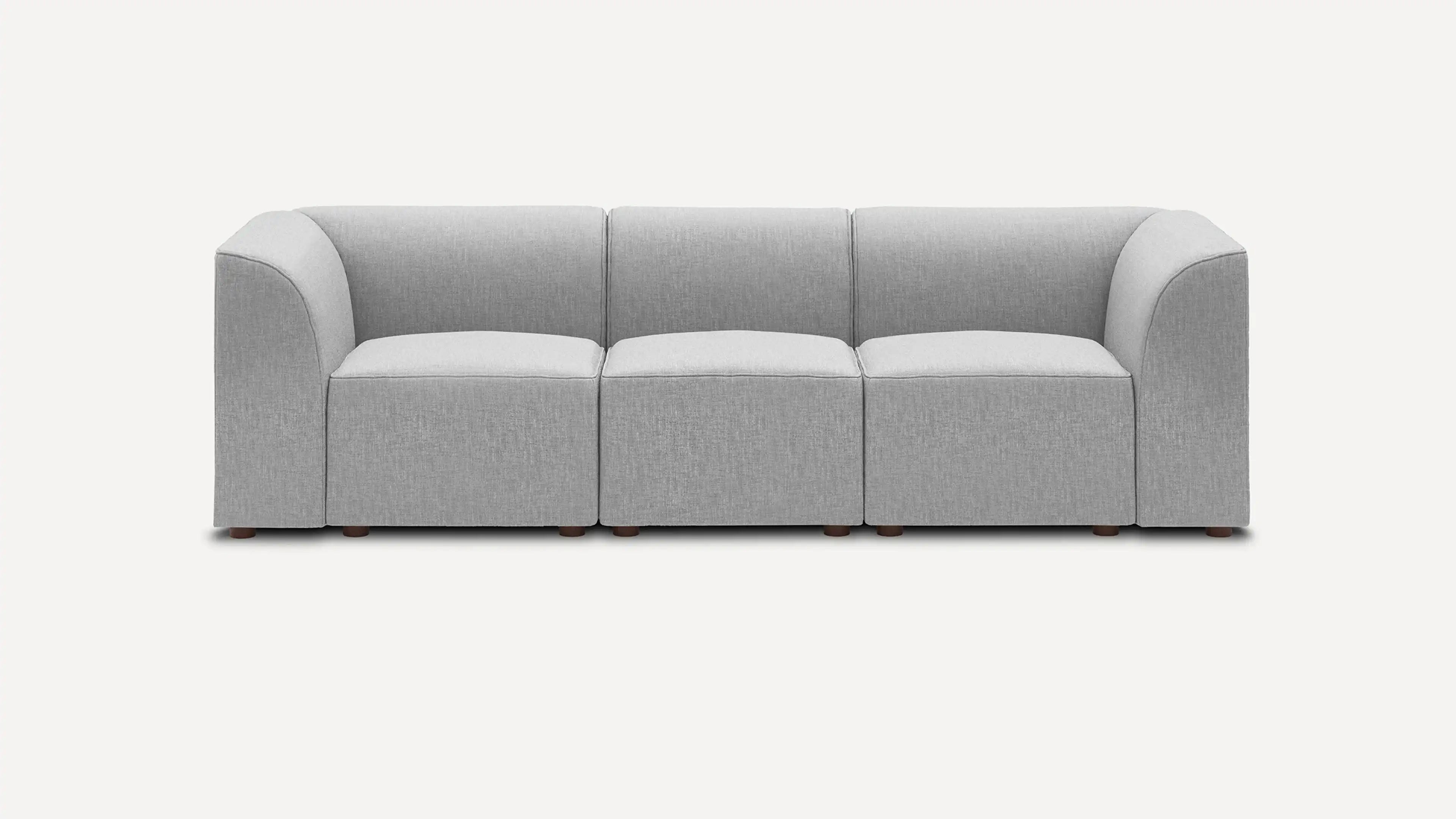Modern gray three-seater sofa with rounded armrests, cushioned seats, and wooden legs on a plain white background.