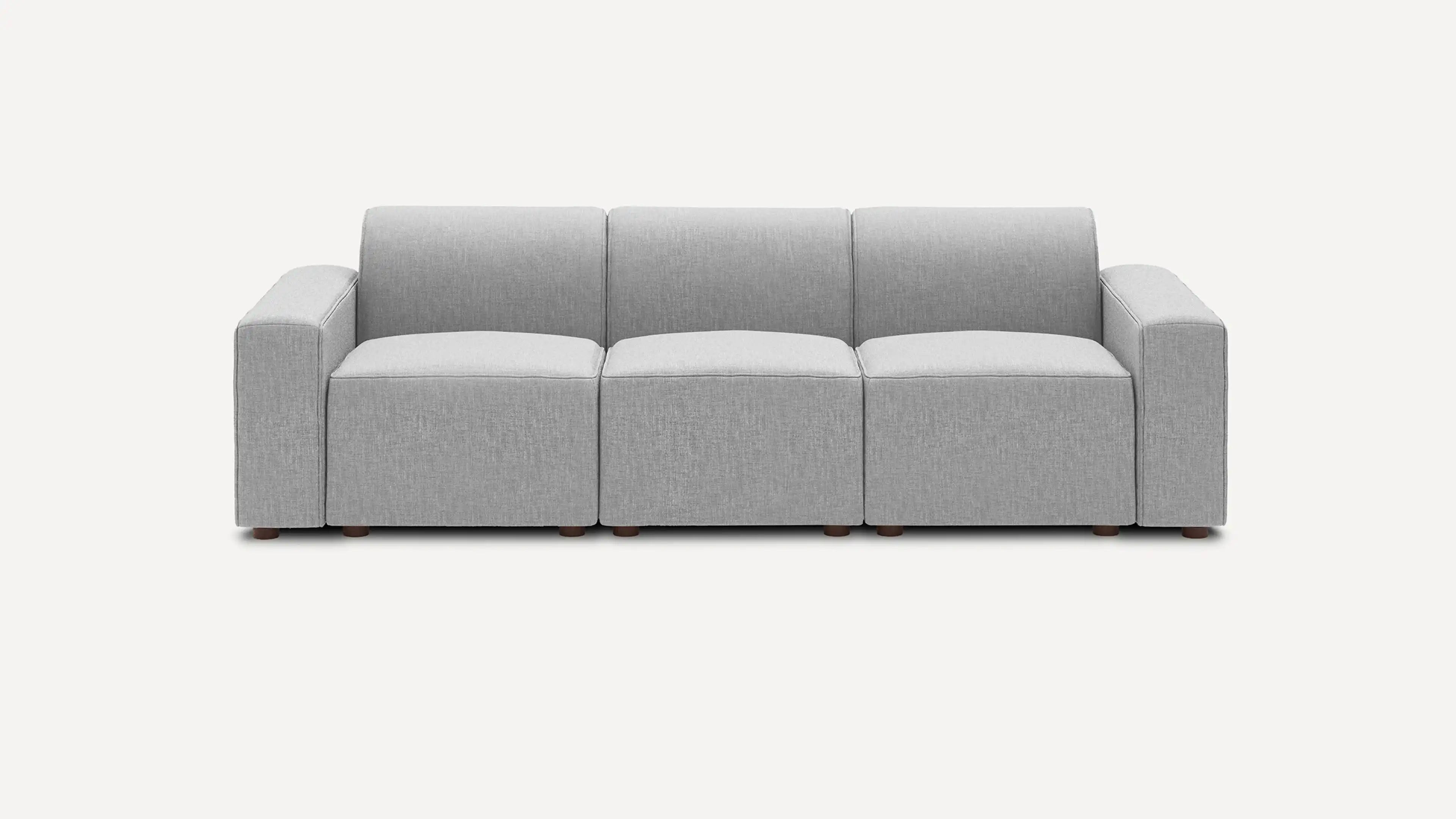 Modern three-seater sofa upholstered in light gray fabric with clean lines and blocky armrests, sitting on small wooden legs.