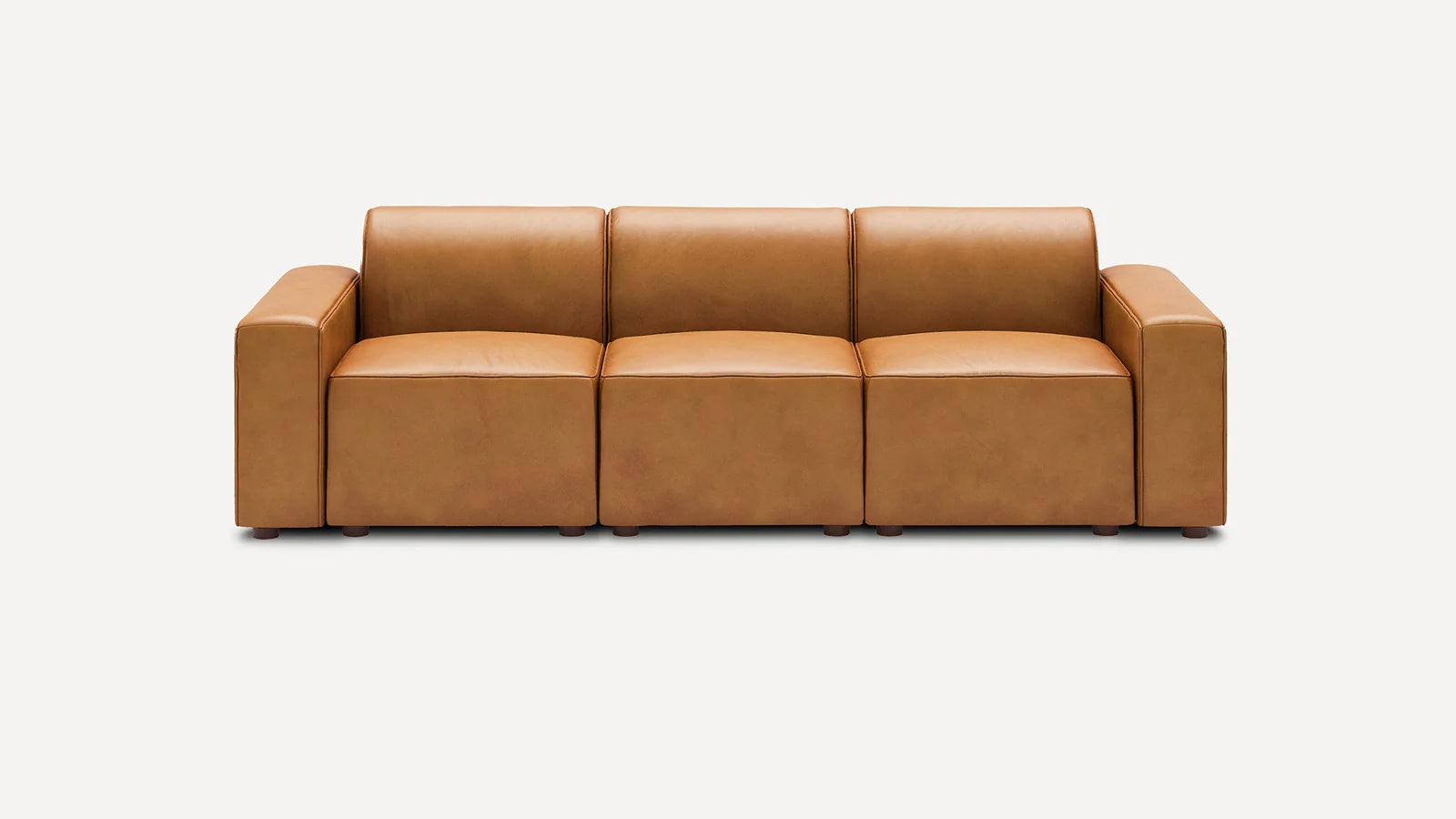 Modern three-seater sofa with clean lines, upholstered in smooth tan leather, featuring wide armrests and low cylindrical legs.