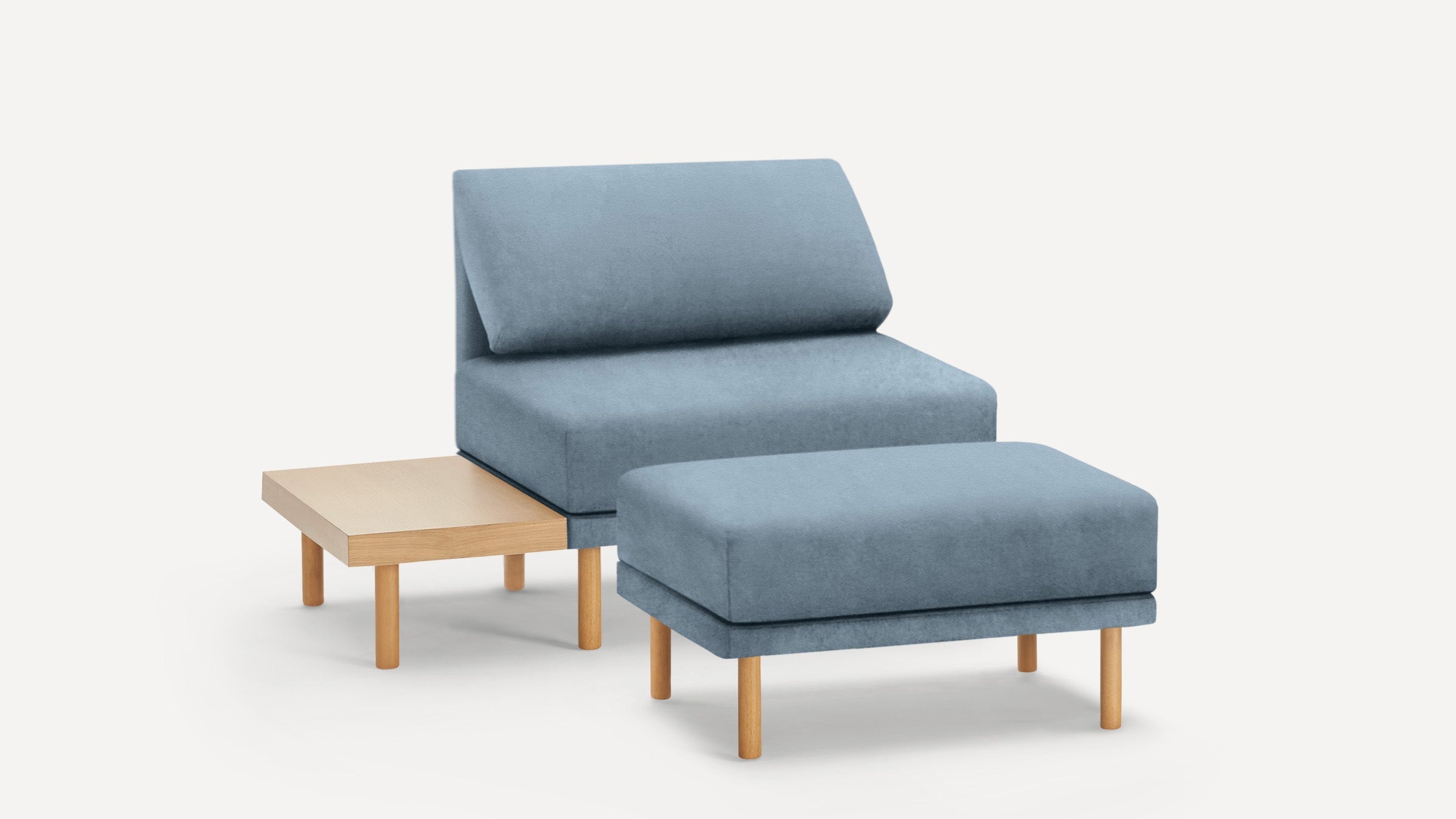 Modern blue upholstered chair with matching ottoman and attached light wood side table, featuring simple wooden legs.