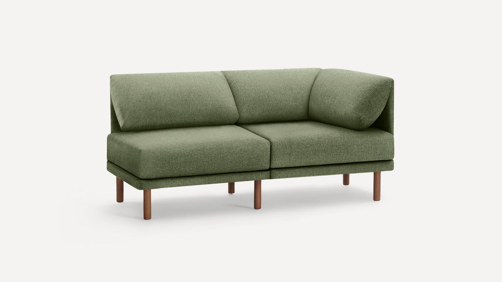 Modern olive green fabric corner sofa with plush cushions and slender wooden legs on white background.