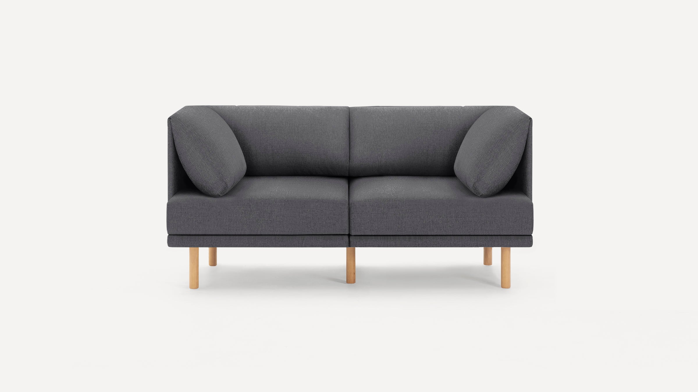 Modern dark gray two-seater sofa with wooden legs and angled armrest cushions, set against a plain white background.