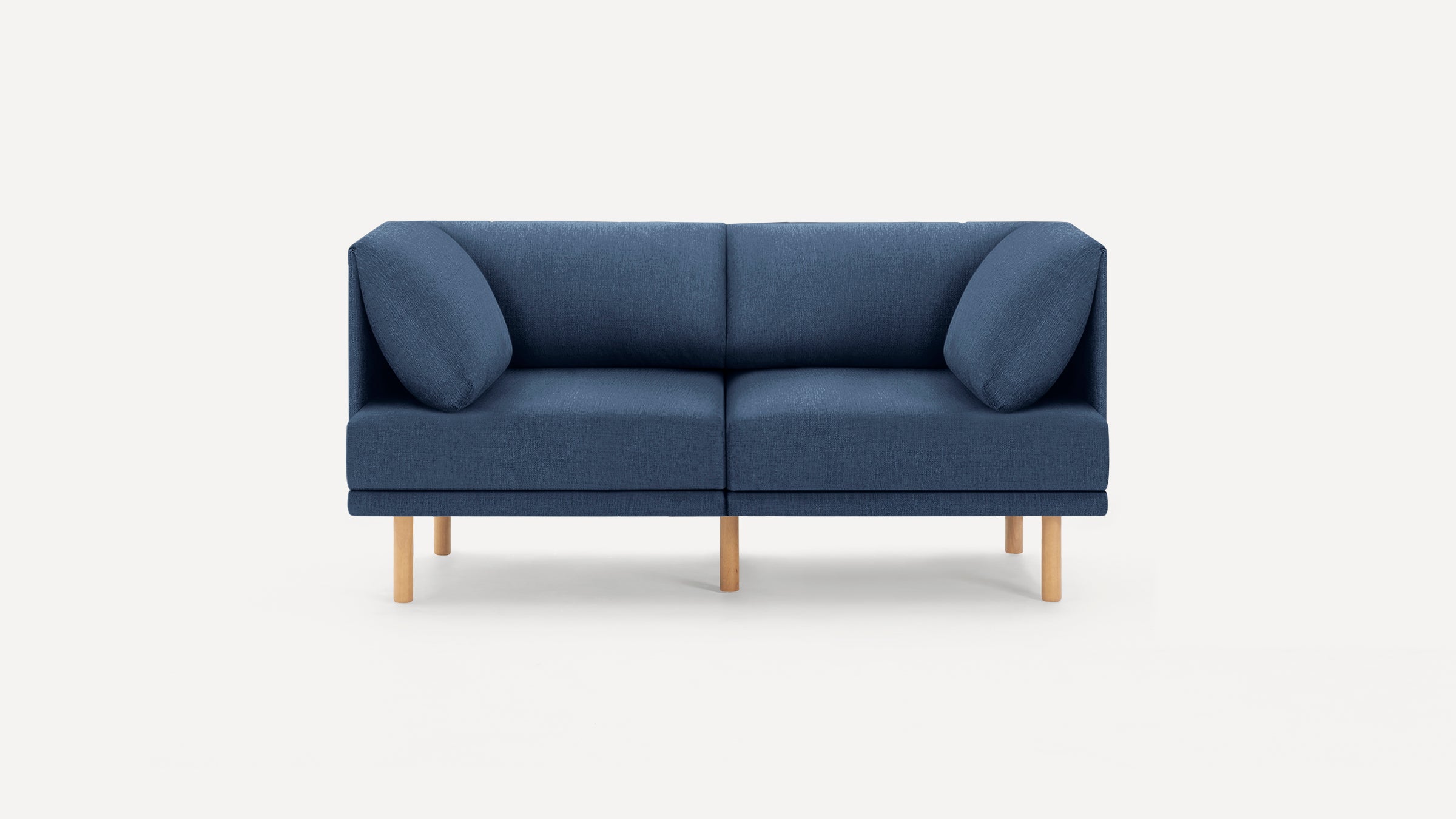 Two-seater modern blue fabric sofa with angled cushions and light wooden legs on a white background.