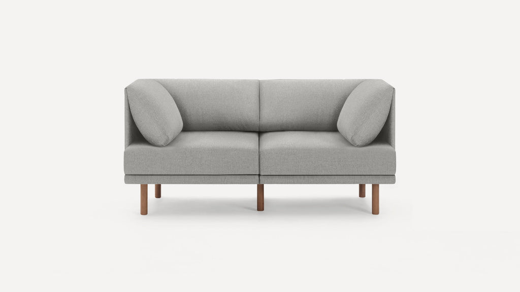 Modern gray fabric two-seater sofa with angled back cushions and wooden legs, set against a white background.
