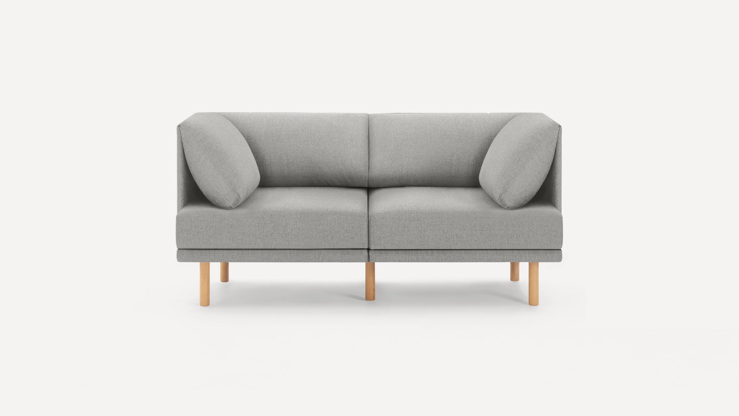 Modern two-seater sofa with light gray fabric upholstery and wooden legs, featuring angled cushions on each side.