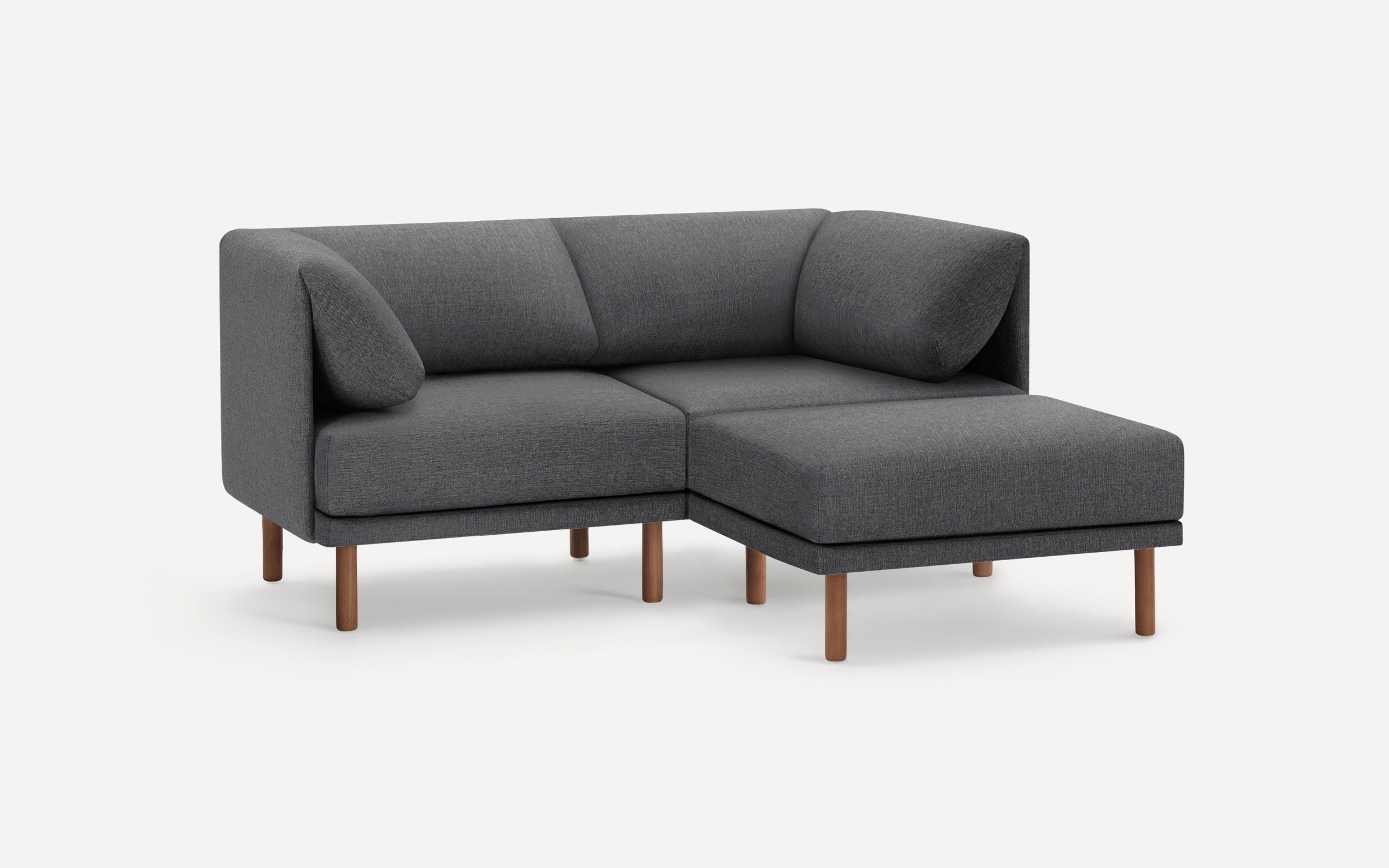 Modern dark gray fabric L-shaped sectional sofa with wooden legs and two matching pillows on a white background.