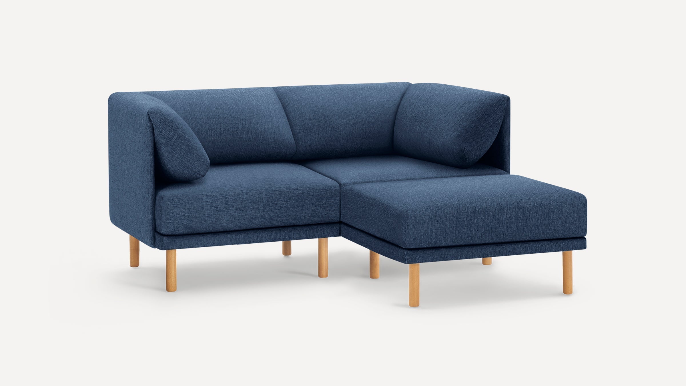 Modern blue fabric L-shaped sectional sofa with low backrest and cylindrical wooden legs on a white background.