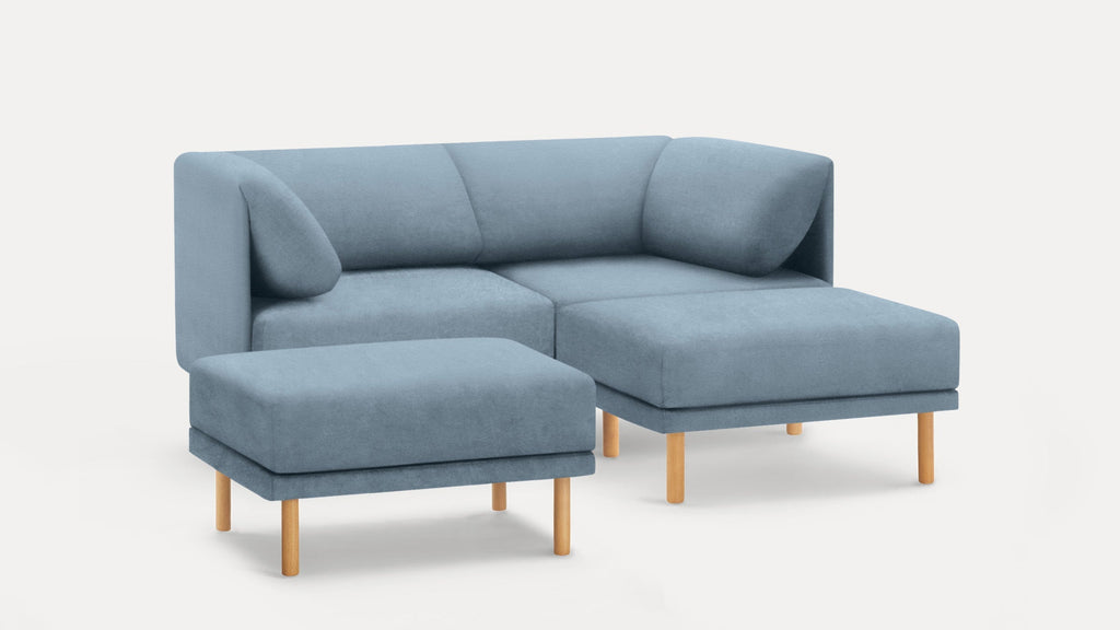 Modern light blue sectional sofa with wooden legs, featuring a chaise lounge and matching ottoman on a white background.