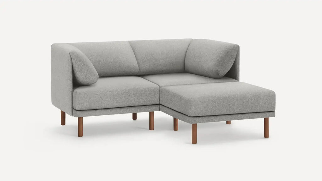 modern light gray fabric sectional sofa with wooden legs and matching ottoman, featuring a clean, minimalist design