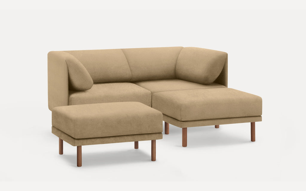 Beige L-shaped sectional sofa with plush cushions and matching ottoman, both featuring wooden legs on a white background.