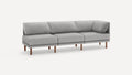 Modern light gray fabric sectional sofa with wooden legs and angled back cushions on a plain white background.