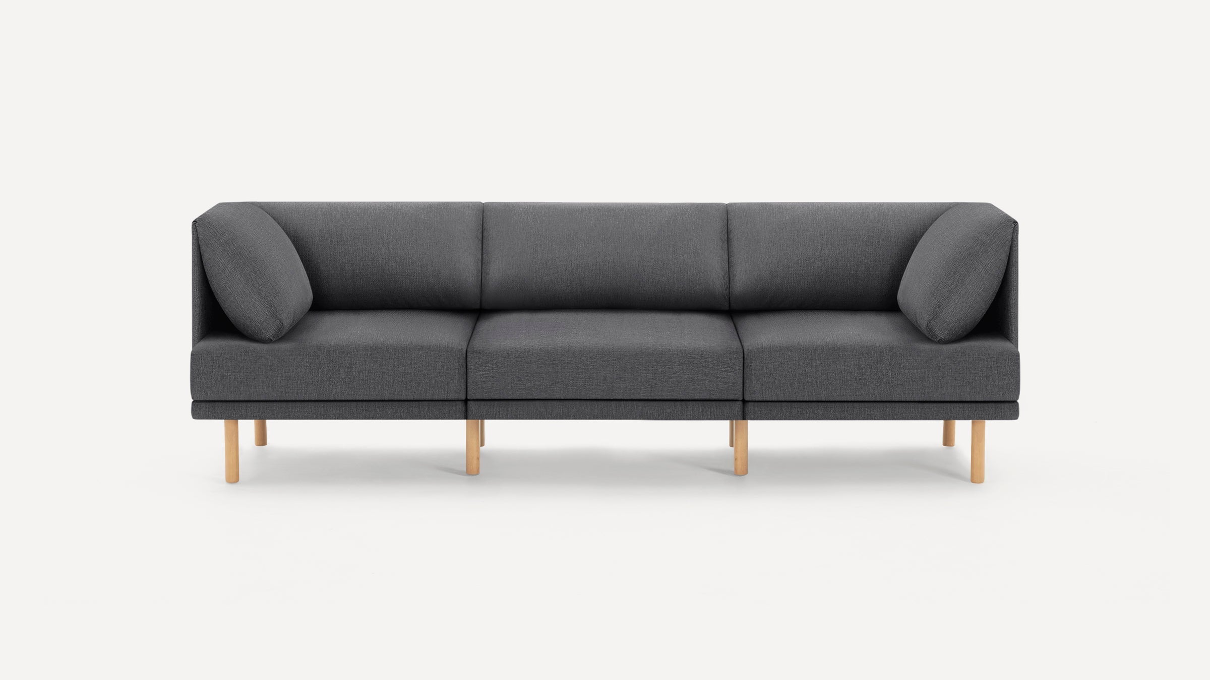Modern three-seater sofa with dark gray fabric upholstery, wooden legs, and angled armrest cushions on both ends.