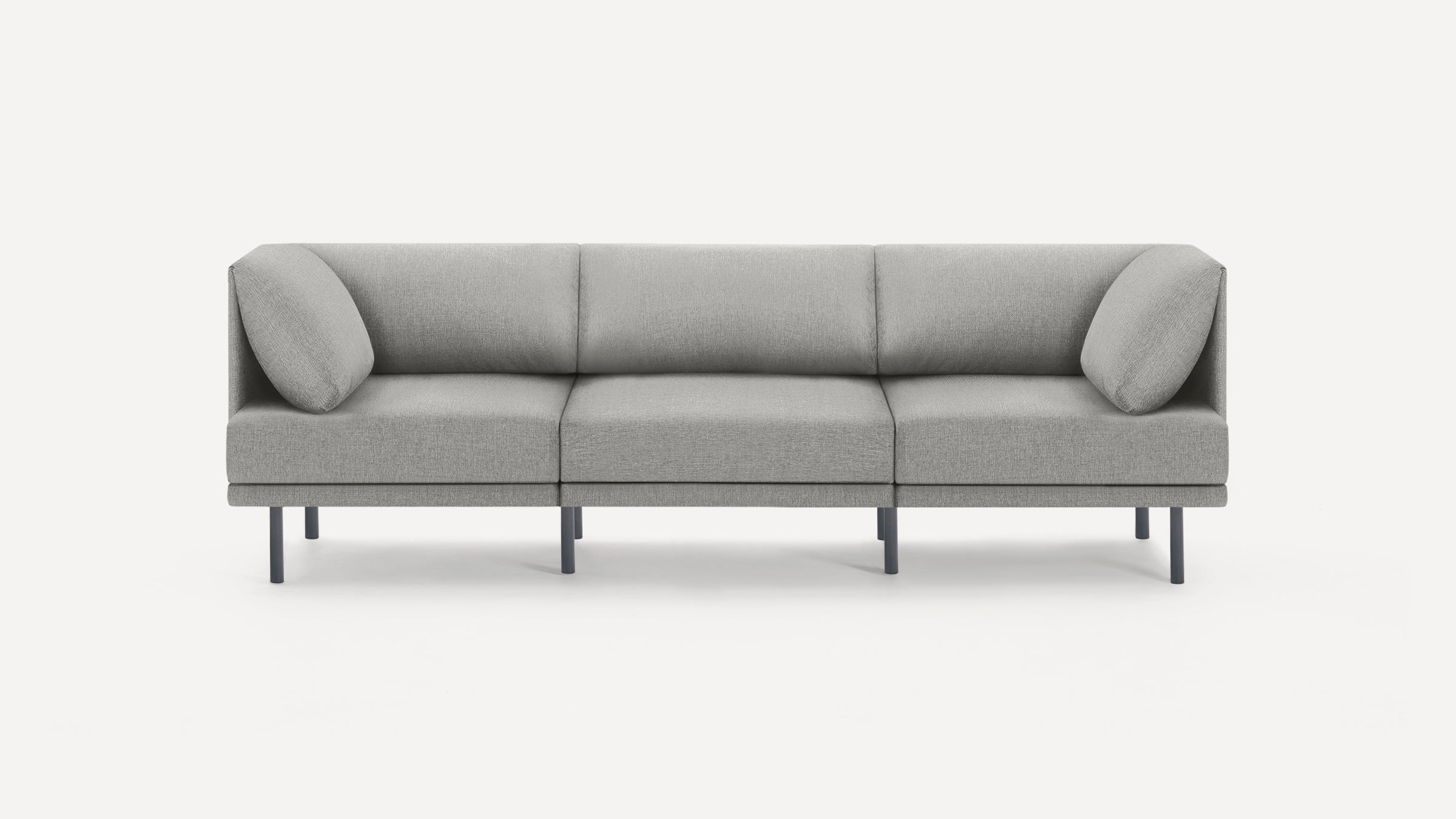 Modern three-seater sofa with light gray fabric upholstery, straight lines, cushioned backrest, angled arm pillows, and slim black metal legs.