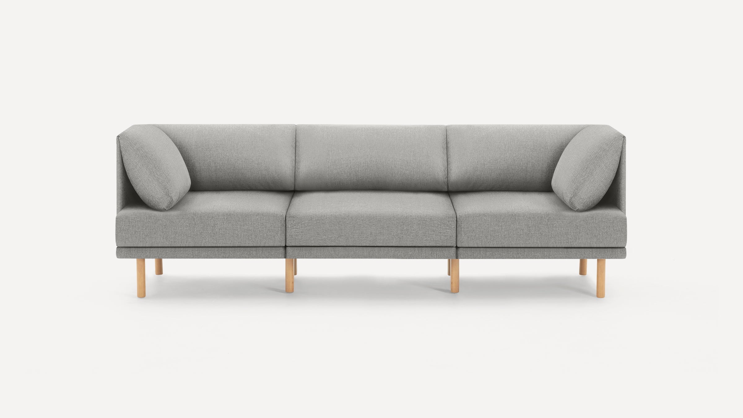 Modern three-seater sofa with light gray fabric upholstery, minimalist design, and light wooden legs, shown on a white background.