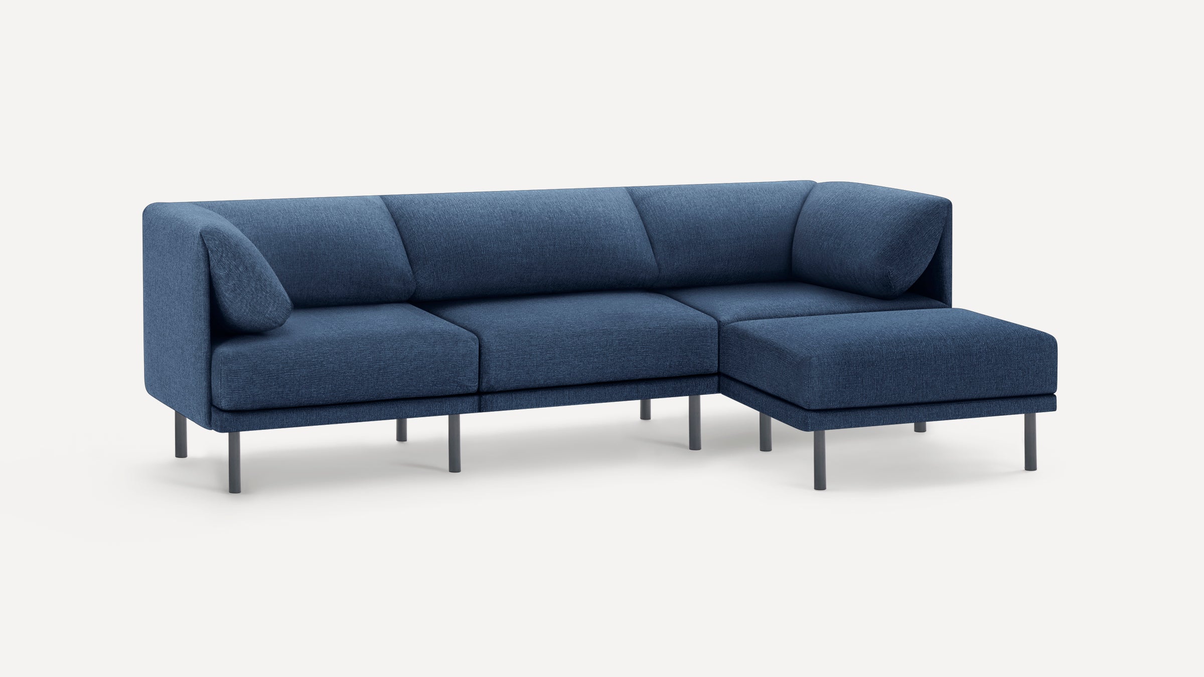 Modern sectional sofa with angled back cushions, upholstered in dark blue fabric, and supported by slim black legs.