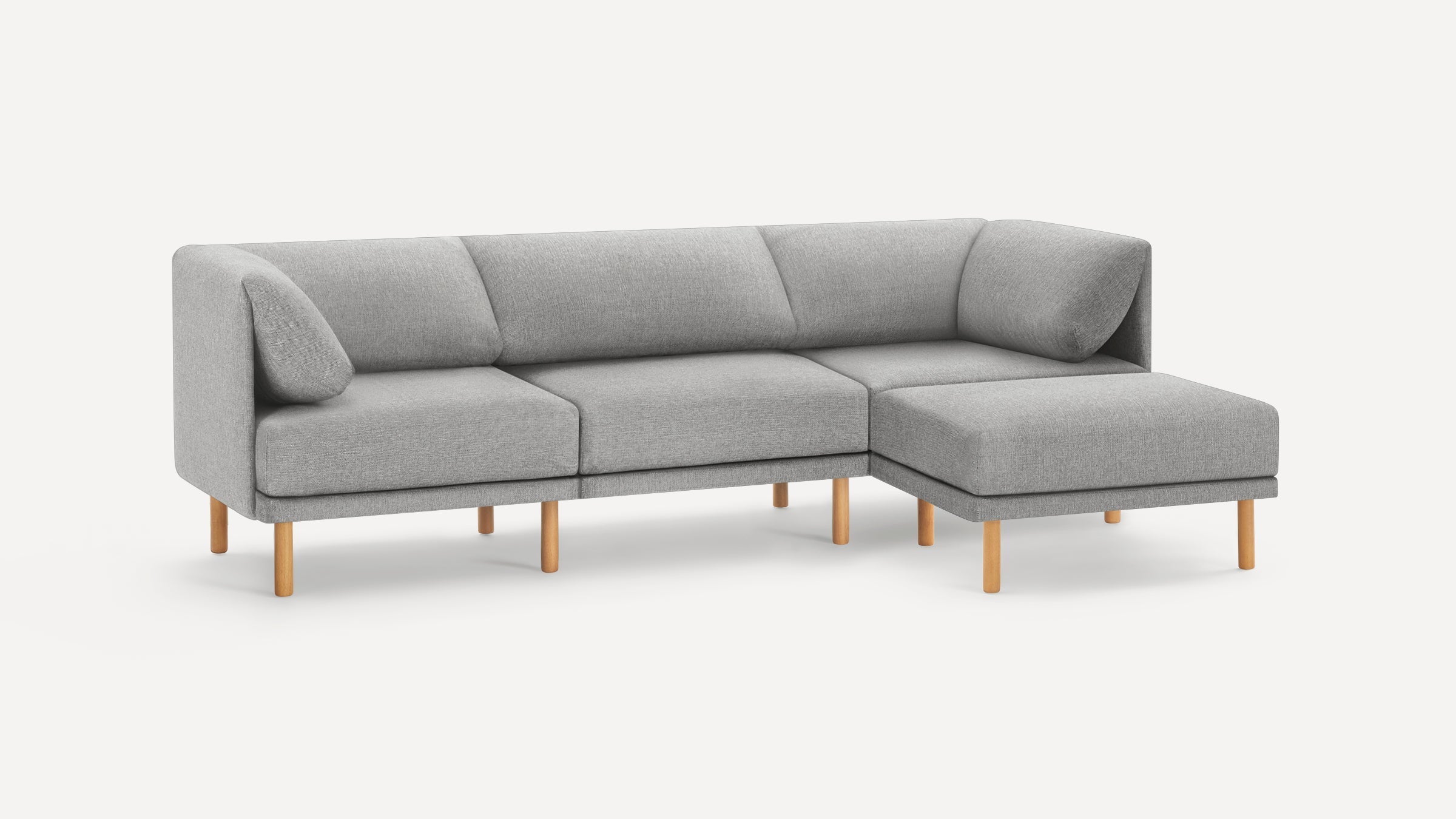 Light gray modern sectional sofa with soft cushions and wooden legs on a plain white background.
