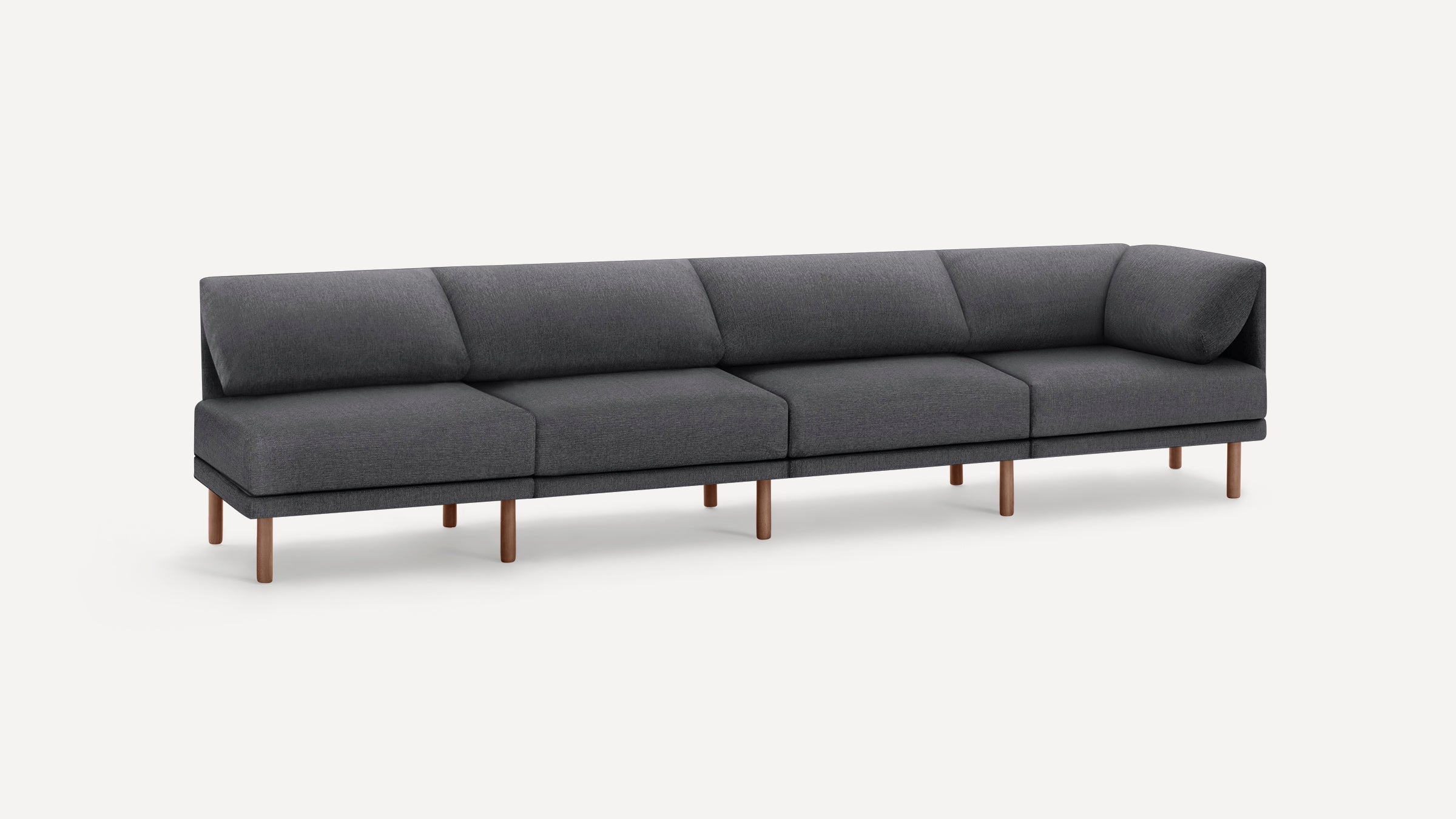 Modern dark gray fabric sectional sofa with low backrest, angled corner seat, and multiple wooden legs on a white background.