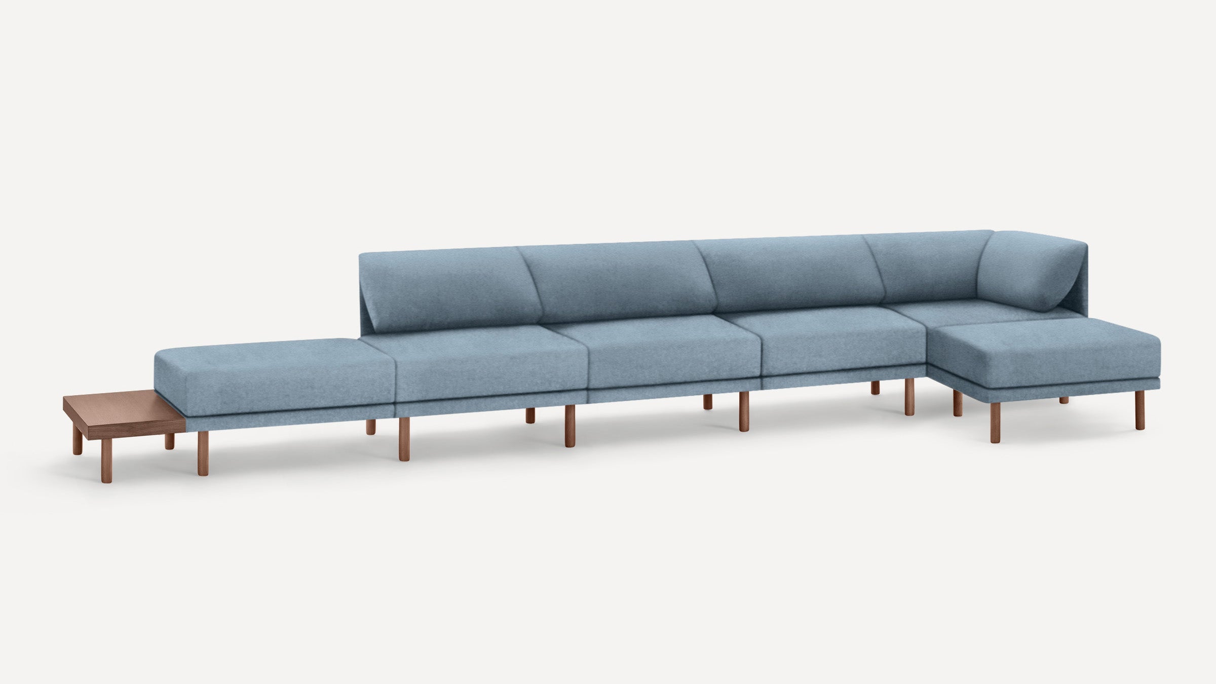 Long modern sectional sofa with light blue upholstery, wooden legs, and an attached small wooden side table on the left end.