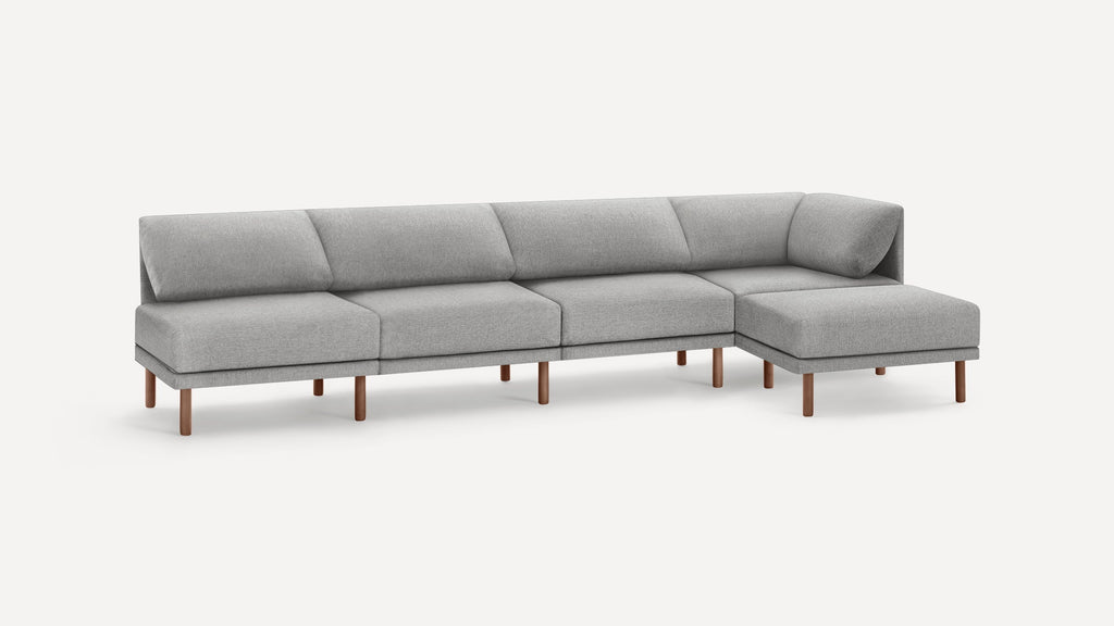 Modern grey fabric sectional sofa with wooden legs, featuring a chaise lounge on the right side.