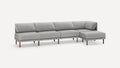 Modern grey fabric sectional sofa with wooden legs, featuring a chaise lounge on the right side.