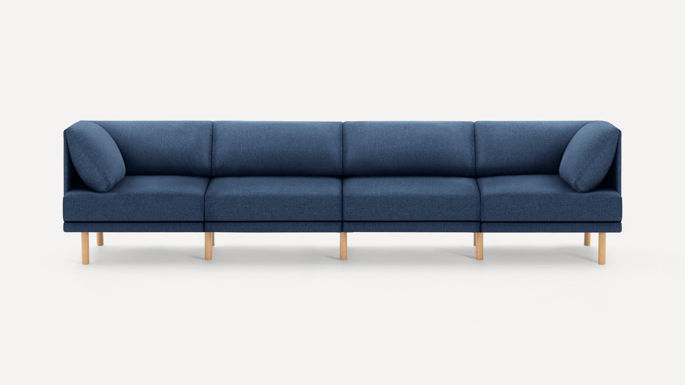 Modern long blue fabric sofa with wooden legs, featuring four sections and rounded armrests on both ends.