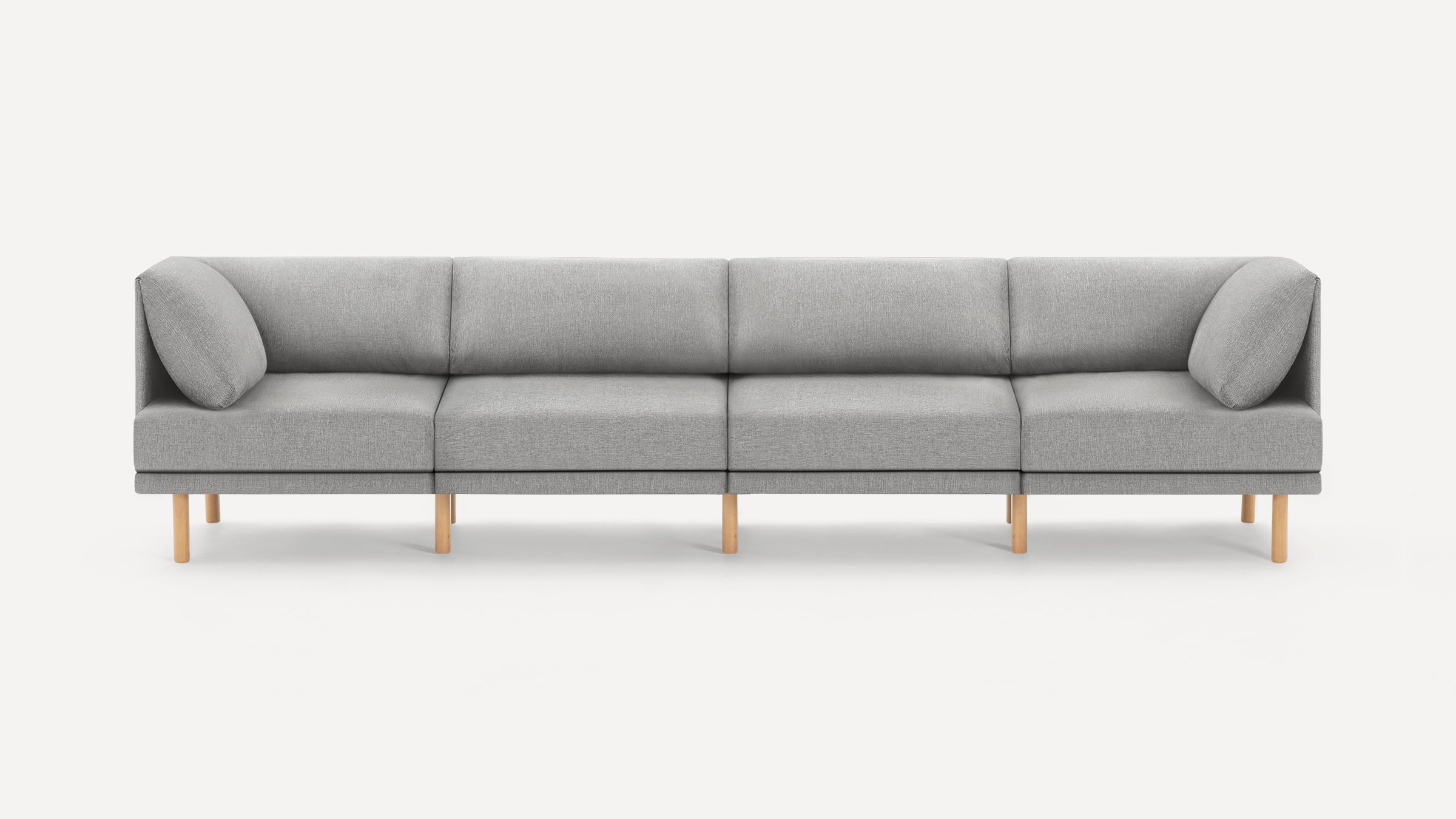 Modern, minimalist light gray fabric sofa with four seating sections and wooden legs, featuring two angled side cushions.