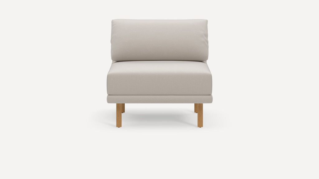 Front view of a modern beige cushioned armless chair with wooden legs on a white background.
