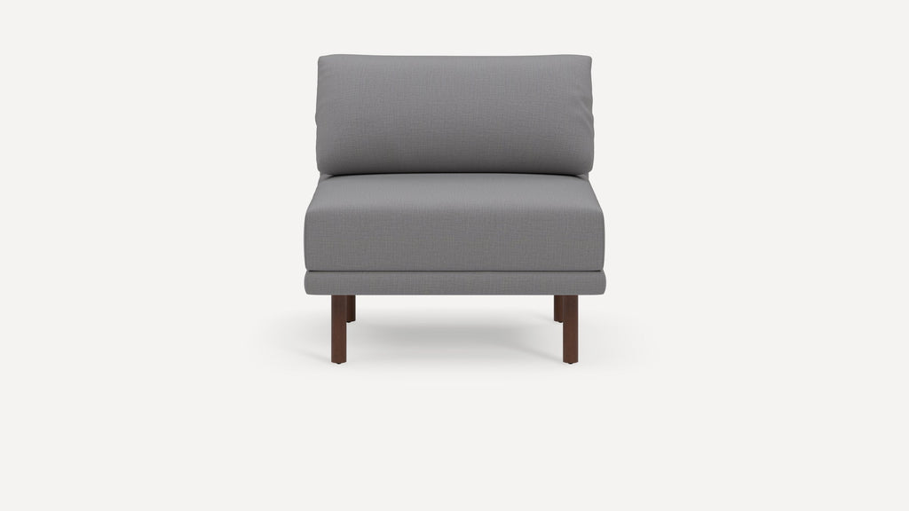 Modern armless grey cushioned chair with wooden legs, featuring a simple, minimalist design on a plain white background.