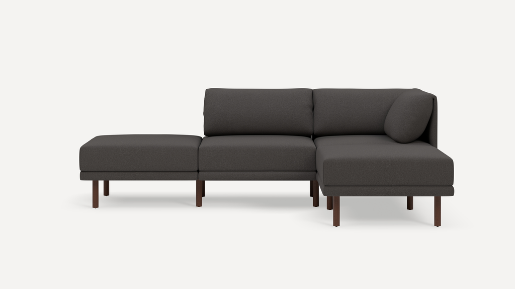 Modern dark gray sectional sofa with wooden legs, featuring a chaise lounge and clean, minimalist design against a white background.