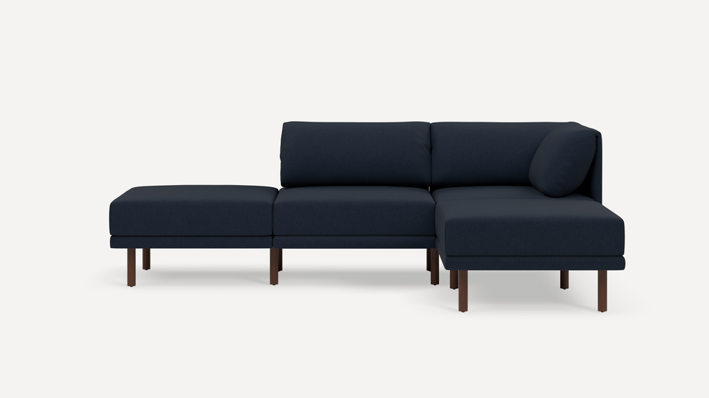 Modern navy blue sectional sofa with wooden legs, featuring a chaise lounge and cushioned backrests.