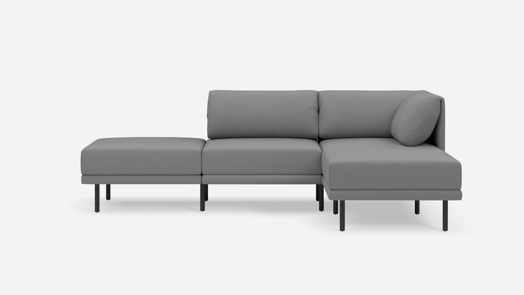 Modern gray sectional sofa with a chaise lounge on the right, low back cushions, and slim black metal legs against a white background.