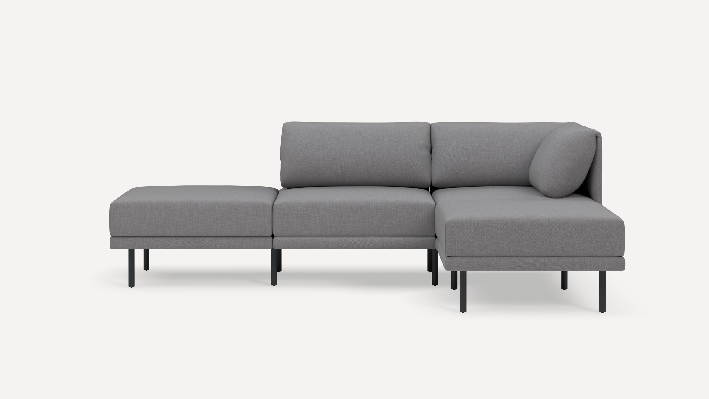 Modern gray sectional sofa with a chaise lounge on the right, low back cushions, and slim black metal legs against a white background.