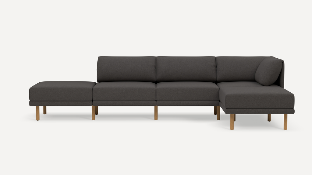 Dark gray modern sectional sofa with wooden legs, featuring three seat cushions and a chaise lounge on the right side.