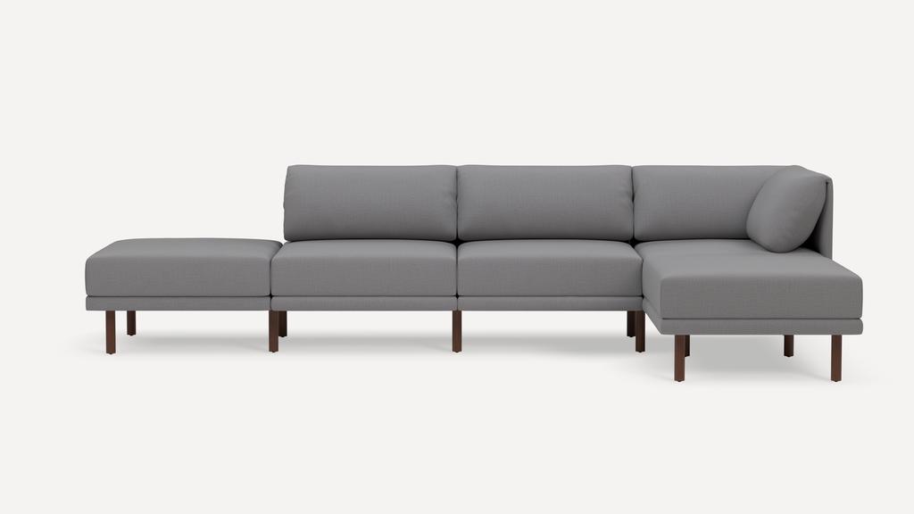 Modern gray sectional sofa with wooden legs, featuring a chaise lounge on the right and a matching ottoman on the left.