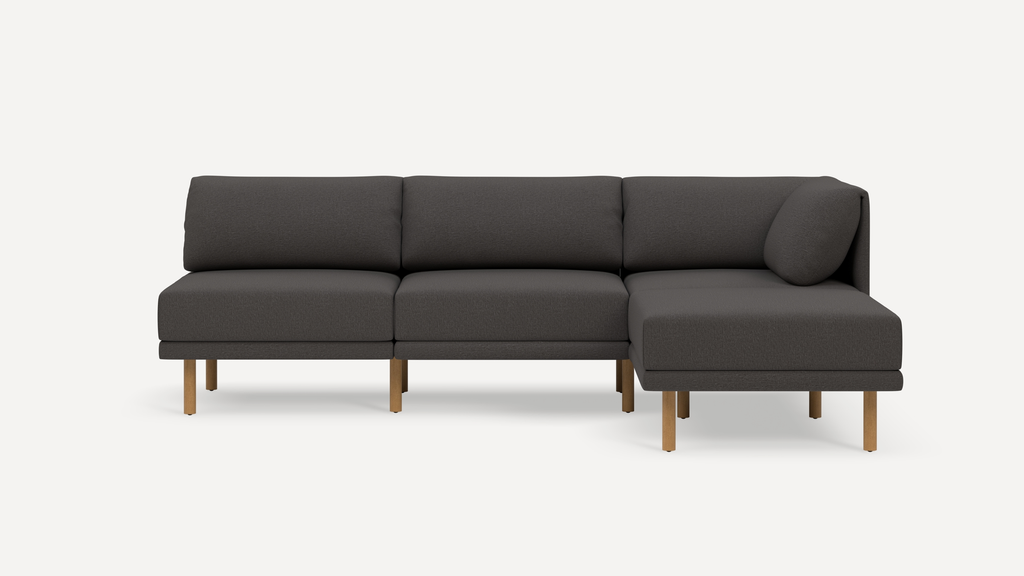 Modern dark gray sectional sofa with three back cushions, wooden legs, and a right-side chaise lounge on a white background.