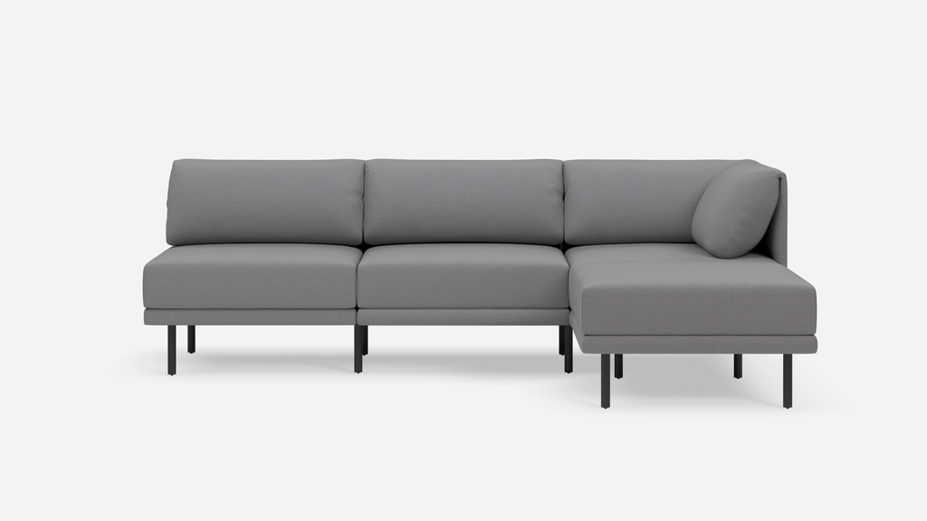 Modern grey sectional sofa with three back cushions and a chaise lounge on the right, supported by slim black metal legs.