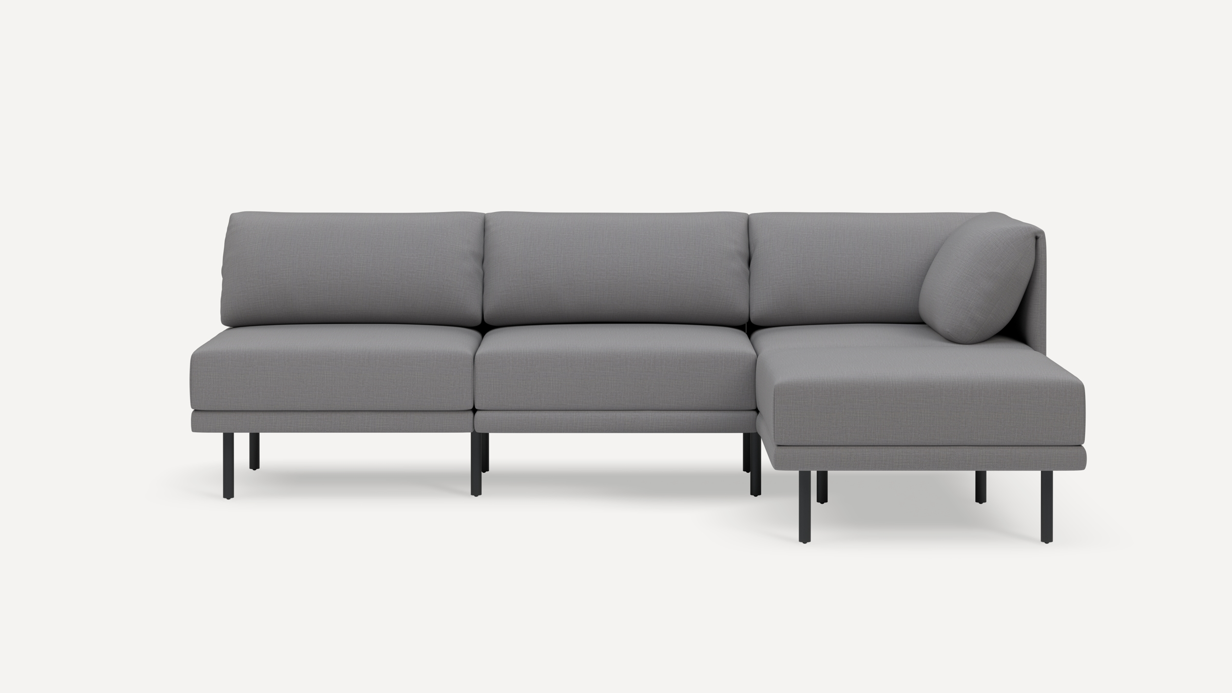 Modern grey sectional sofa with three back cushions and a chaise lounge on the right, supported by slim black metal legs.