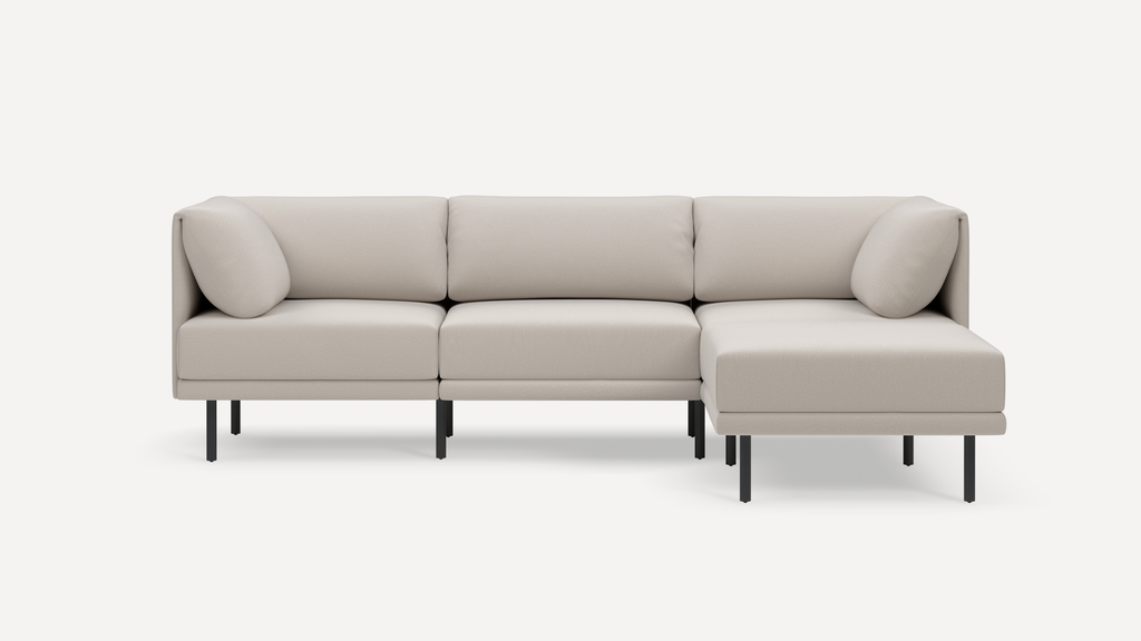 Modern beige sectional sofa with clean lines, black metal legs, and plush cushions including two corner pillows.