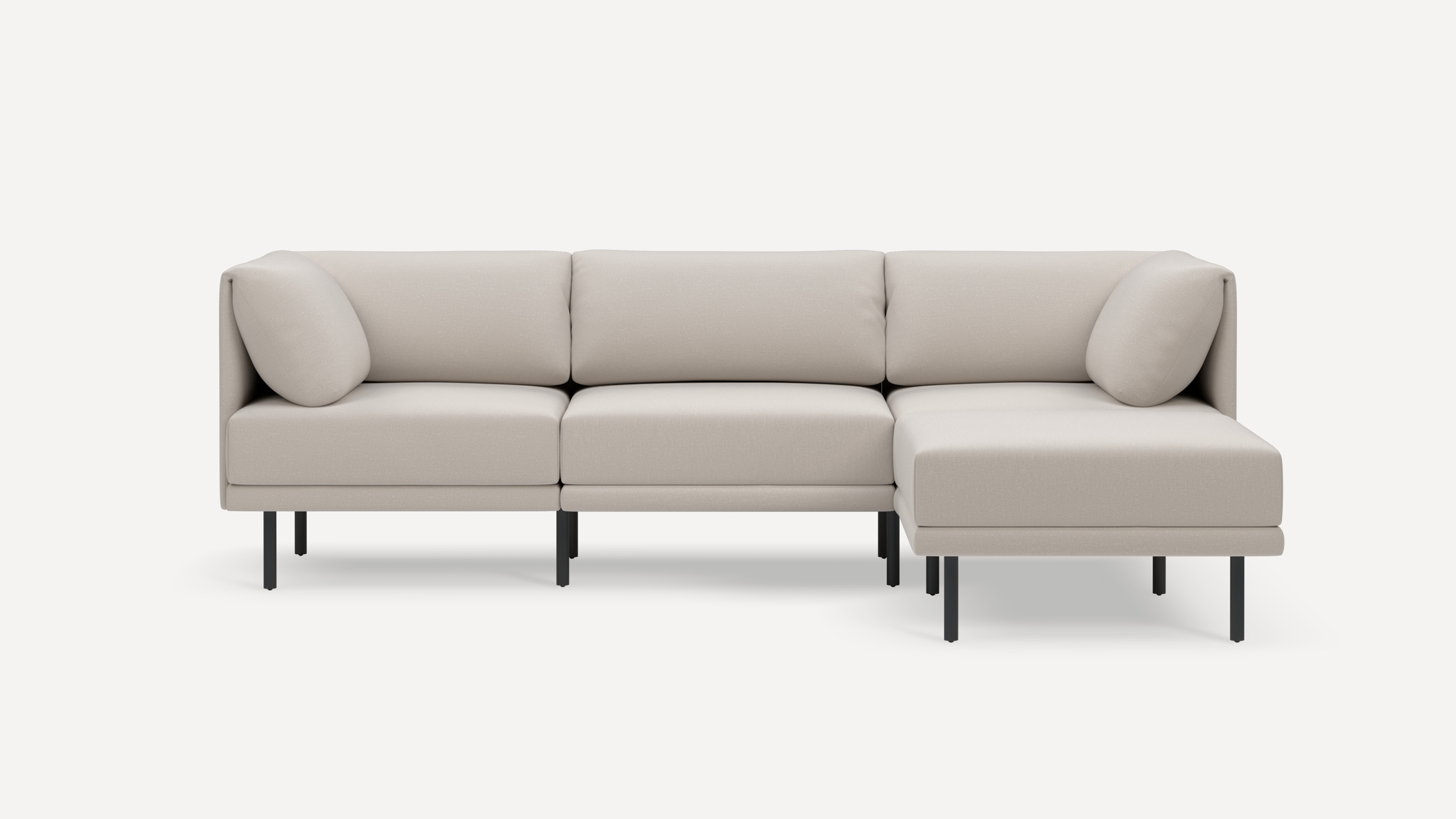Modern beige sectional sofa with clean lines, black metal legs, and plush cushions including two corner pillows.
