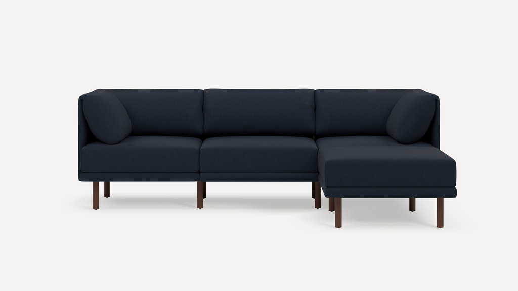 Modern navy blue L-shaped sectional sofa with wooden legs and cushioned back and armrests.