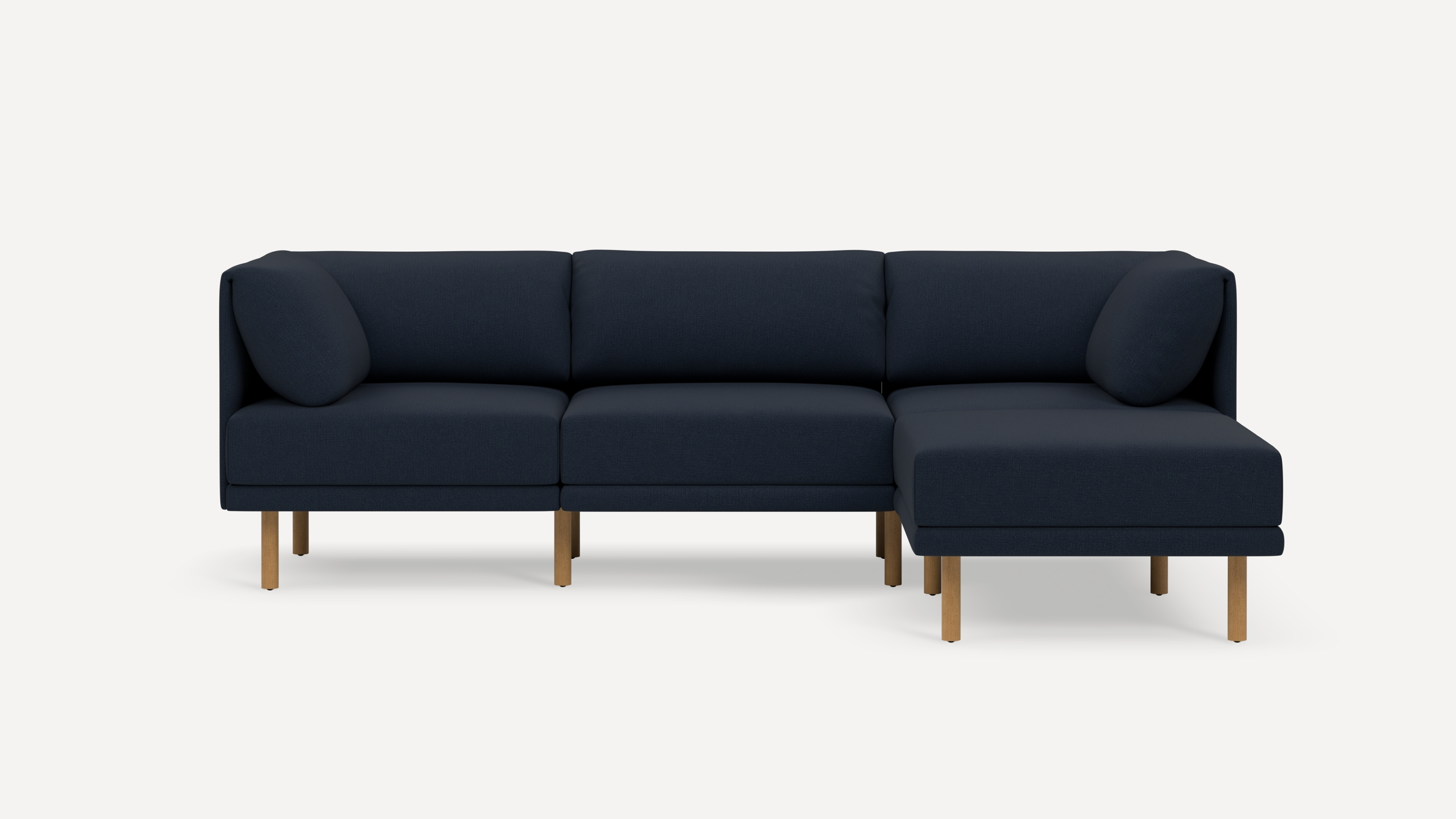 Modern navy blue sectional sofa with wooden legs, featuring three seat cushions and rounded back pillows, against a plain white background.
