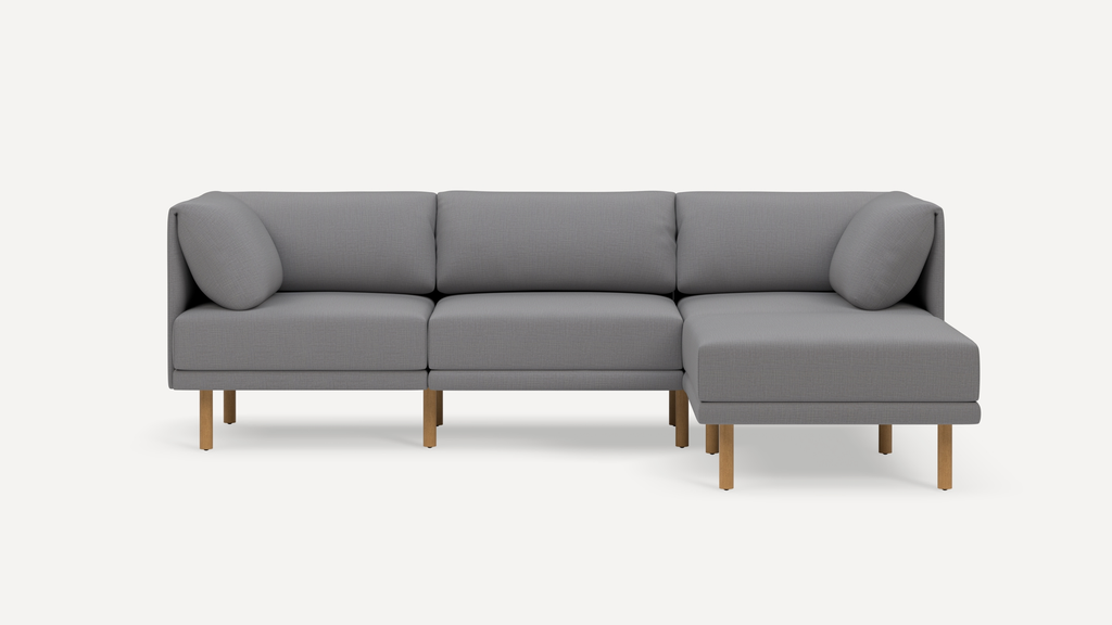 Modern gray fabric sectional sofa with wooden legs, cushioned seats, and backrest pillows, featuring a right-side chaise lounge.
