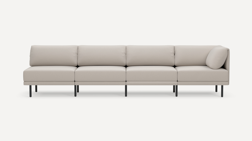 Modern beige fabric sectional sofa with clean lines, black metal legs, four seats, and a single round pillow on the right side.