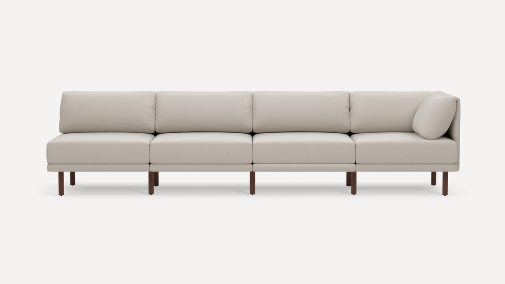 Modern four-seat sectional sofa with beige upholstery and wooden legs, featuring clean lines and plush back cushions.