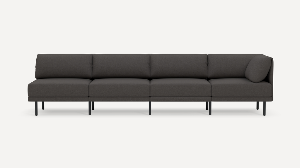 Modern dark gray four-seater sectional sofa with slim black metal legs and plush cushioned back and seat, isolated on white background.