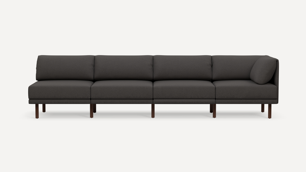 Modern dark gray sectional sofa with four cushioned seats, wooden legs, and a corner backrest pillow.