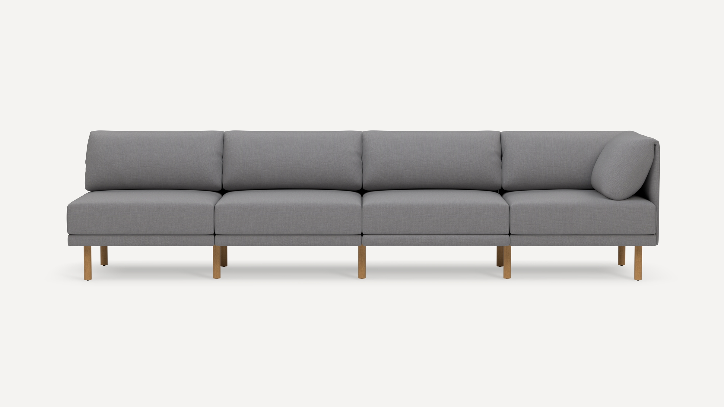 Modern four-seat grey fabric sofa with wooden legs and a single angled cushion on the right side.