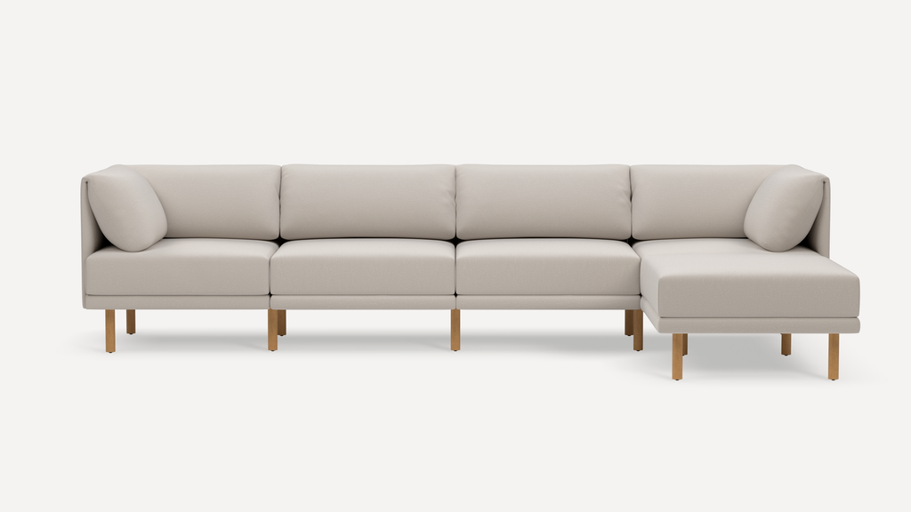 Modern light beige sectional sofa with wooden legs, featuring clean lines and plush cushions, including a right-side chaise lounge.