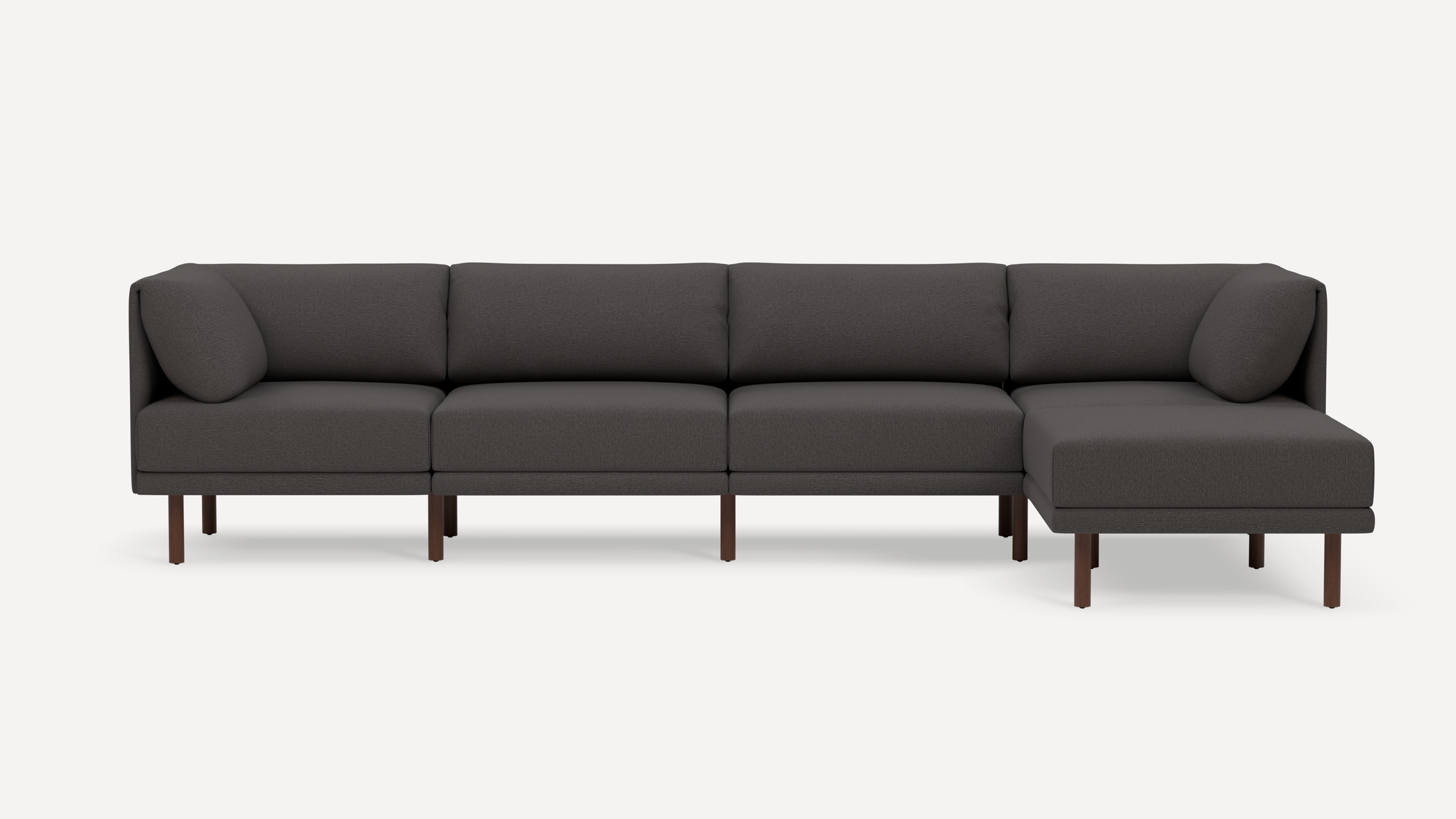 Modern dark gray sectional sofa with wooden legs, featuring cushioned seats, backrests, and angled armrest pillows.