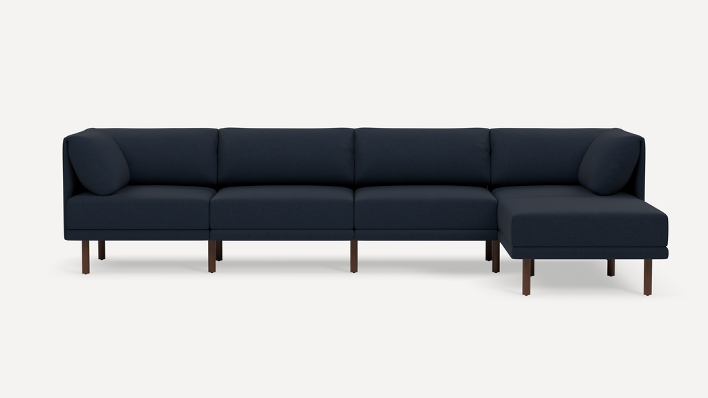 Modern navy blue sectional sofa with clean lines, angled cushions, and wooden legs, featuring a right-side chaise lounge.